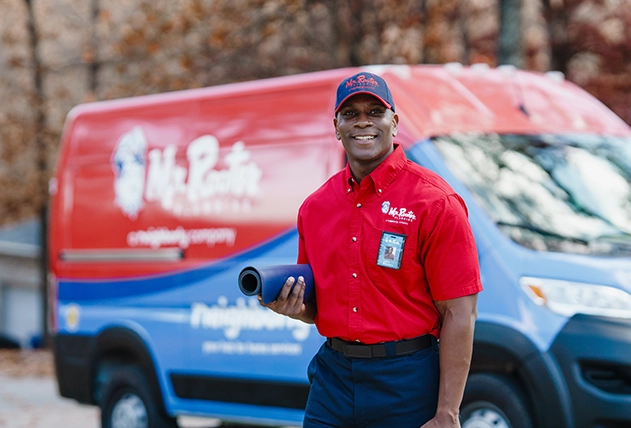 Mr. Rooter employee smiling and waving from a branded van.