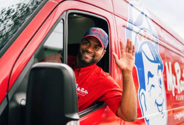 Mr. Rooter employee smiling and waving from a branded van.