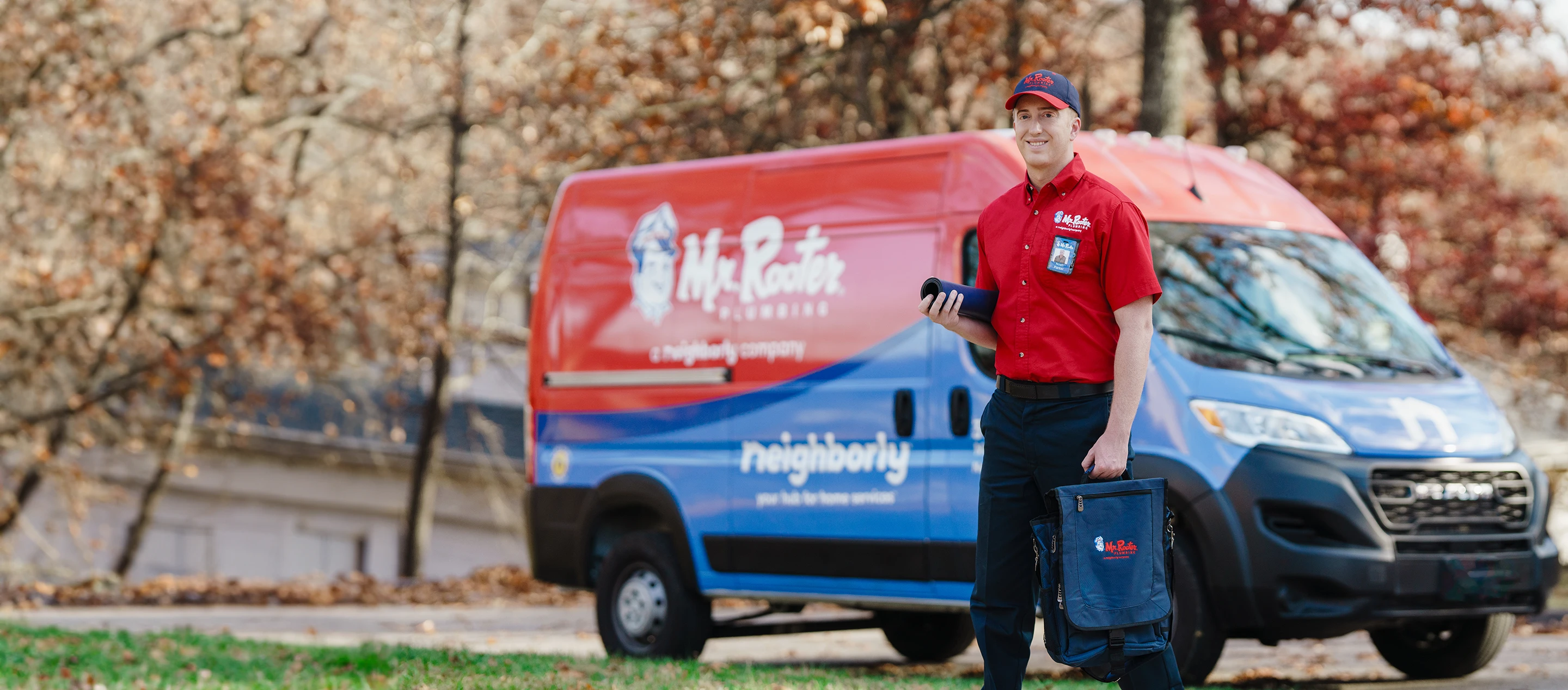 Mr. Rooter technician standing beside a branded van.