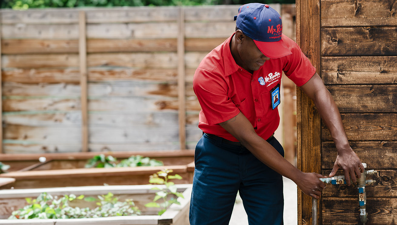 Mr. Rooter technician adjusting an outdoor water valve.