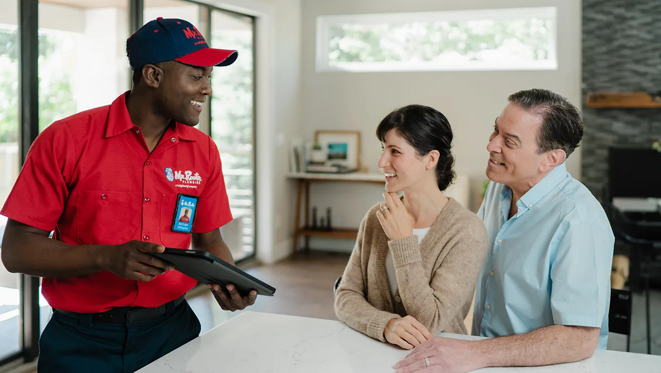 Mr. Rooter technician showing customers information on a tablet.