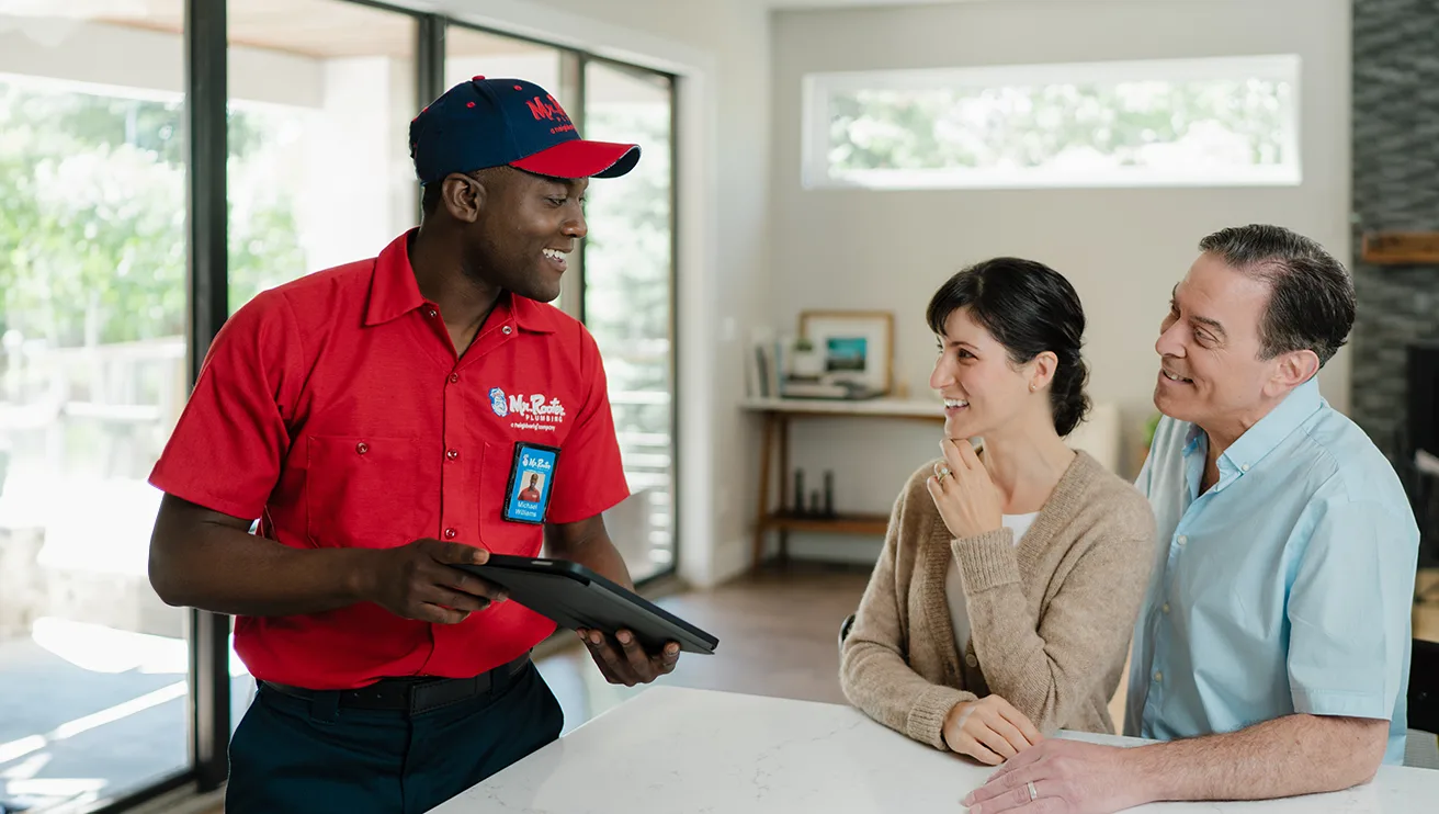 Two Mr. Rooter customers speaking with a technician about water shut off services.