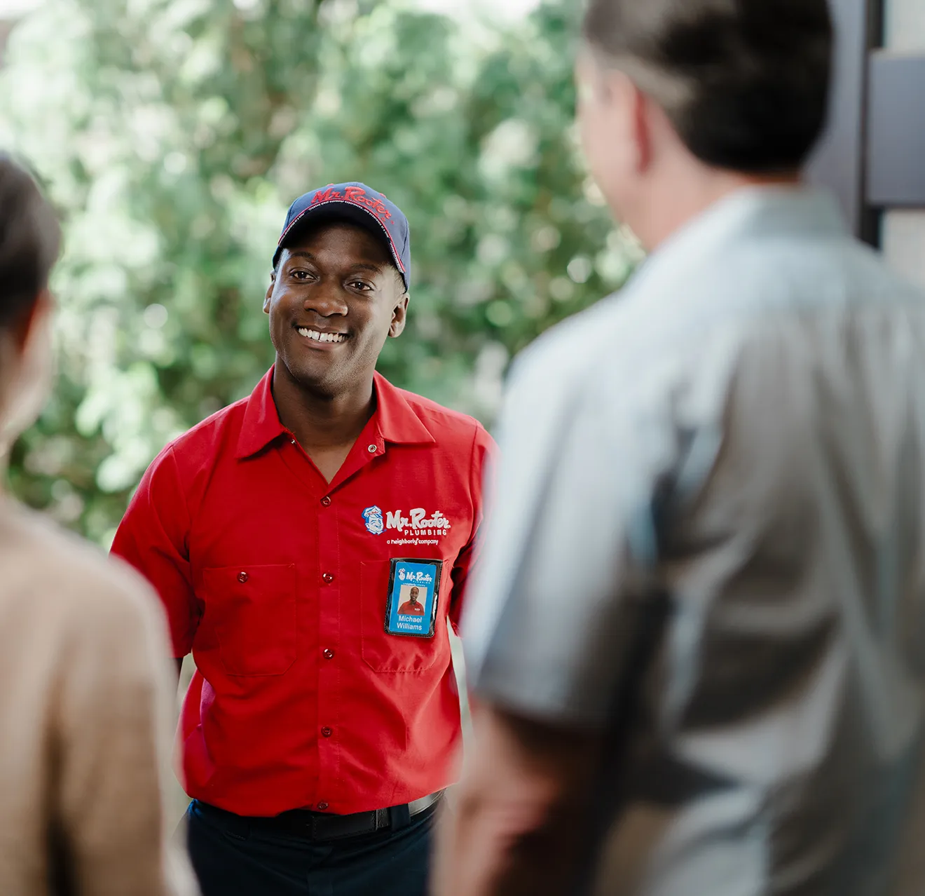 Two customers greeting a Mr. Rooter technician at their front door.