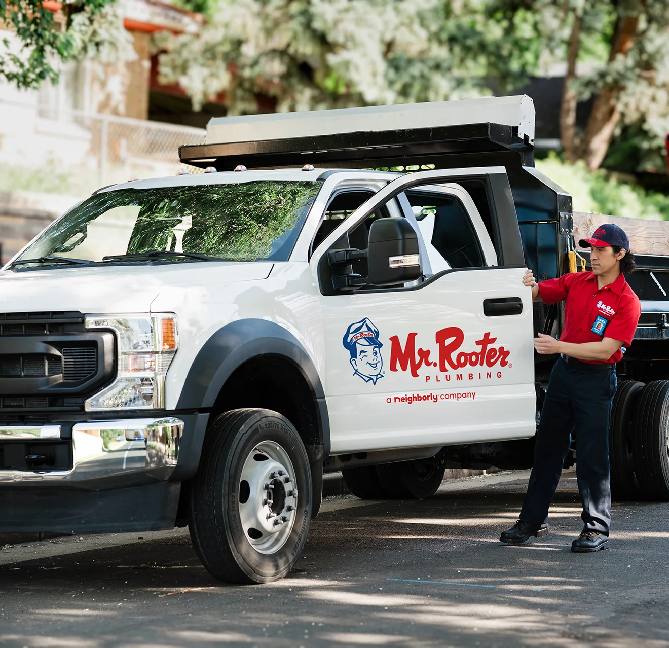 White Mr. Rooter truck parked with technician standing beside it.