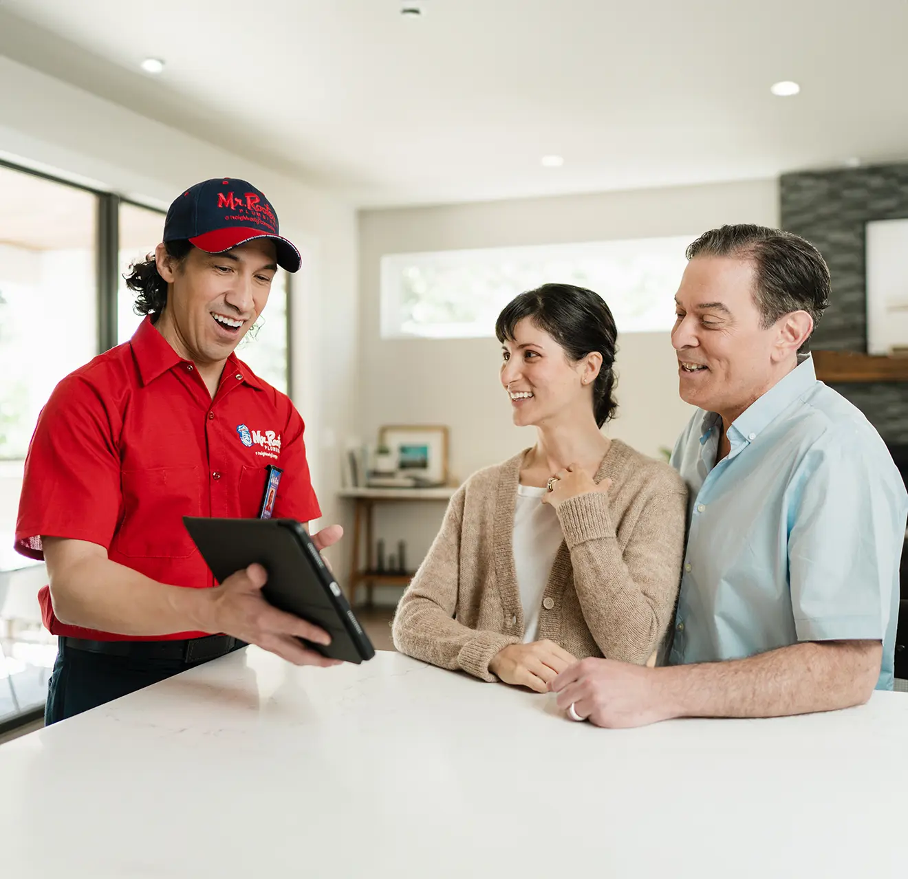 Mr. Rooter technician going over water heater repair options on a tablet with two customers,