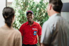 Two customers greeting a Mr. Rooter professional at the front door.