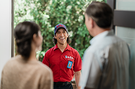Mr. Rooter employee greeting two customers at their front door.