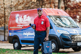 Mr. Rooter technician standing beside a branded van.