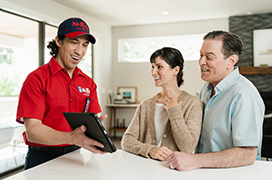 Mr. Rooter technician showing customers a service plan on a tablet.