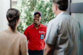 Two customers greeting a Mr. Rooter technician at the front door of their home.