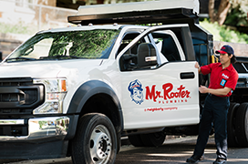 Mr. Rooter technician standing beside a white work truck.