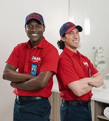 Two Mr. Rooter professionals standing back to back with their arms crossed.