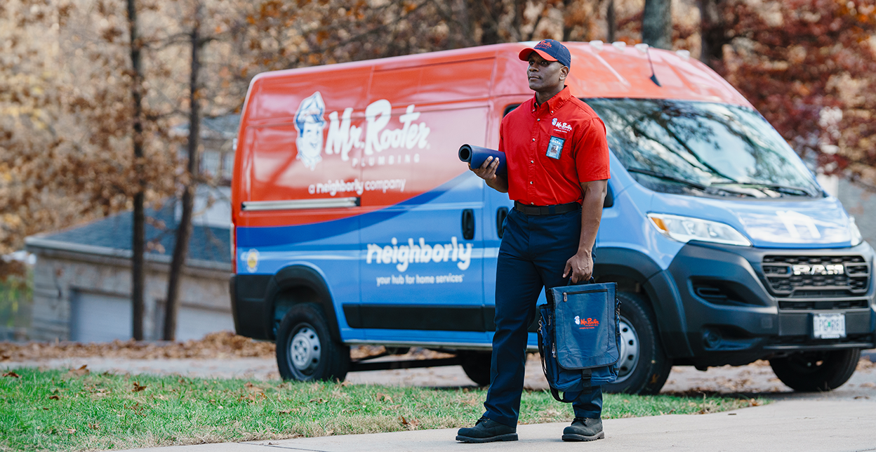 Mr. Rooter technician standing in front of a branded work van.