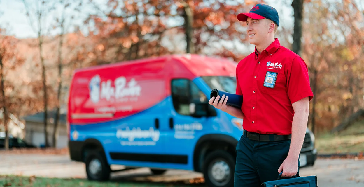 Mr. Rooter technician standing beside a branded van.