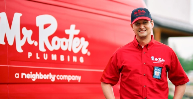 Mr. Rooter service professional standing beside a branded van.