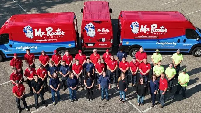 The Mr. Rooter Plumbing of The Twin Cities team standing in front of three service vans.