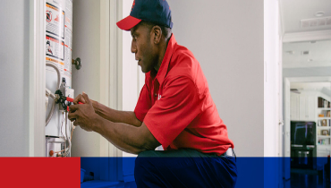 Male Mr. Rooter plumbing service technician repairing residential home water heater.