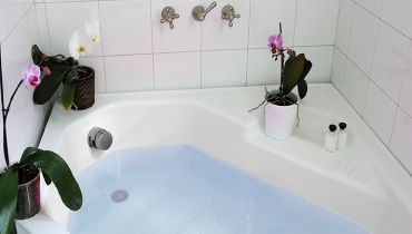 A person testing the water coming out of a bathtub faucet.