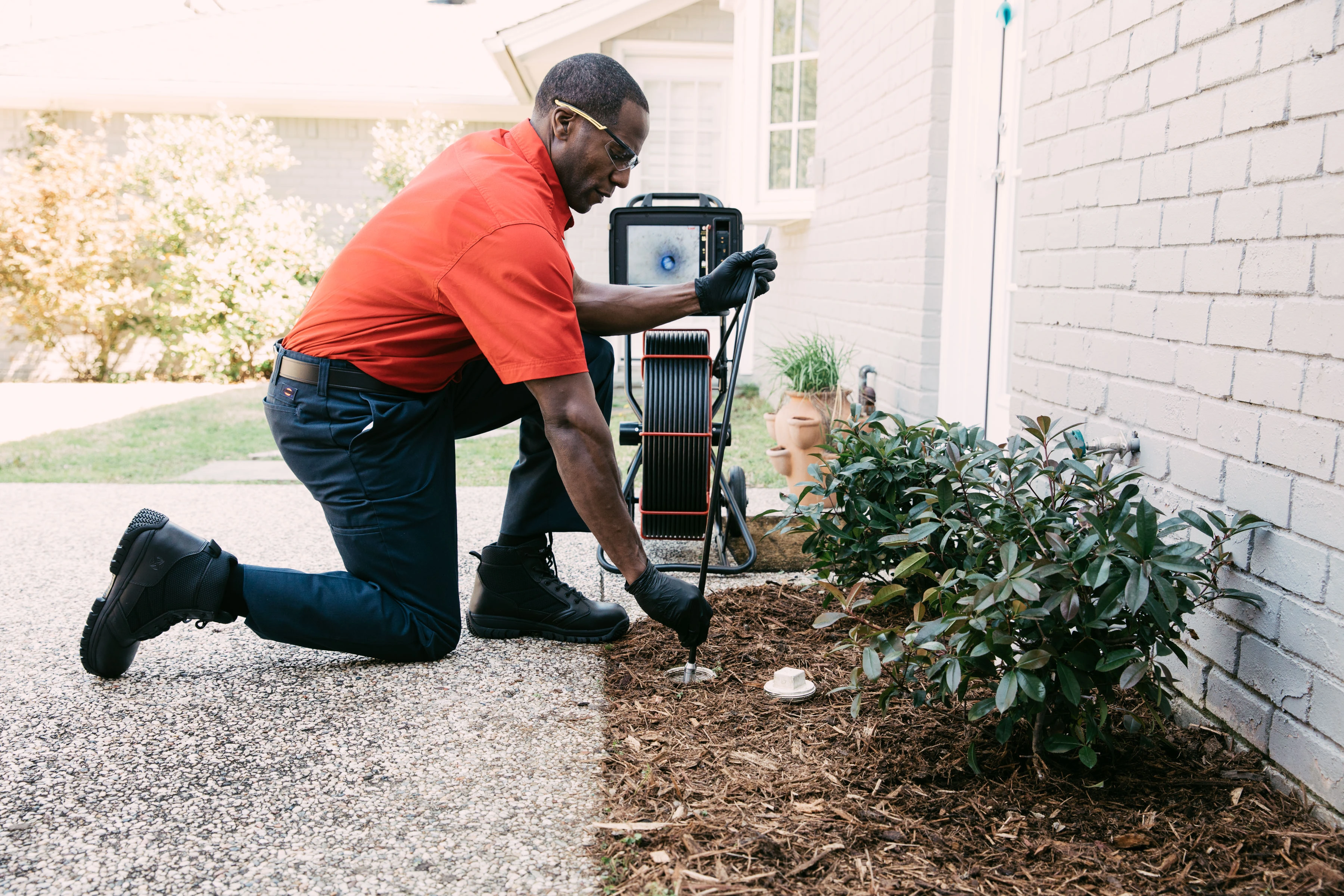 Mr. Rooter Plumbing professional running a sewer camera line into an outdoor cleanout to locate pipe damage.
