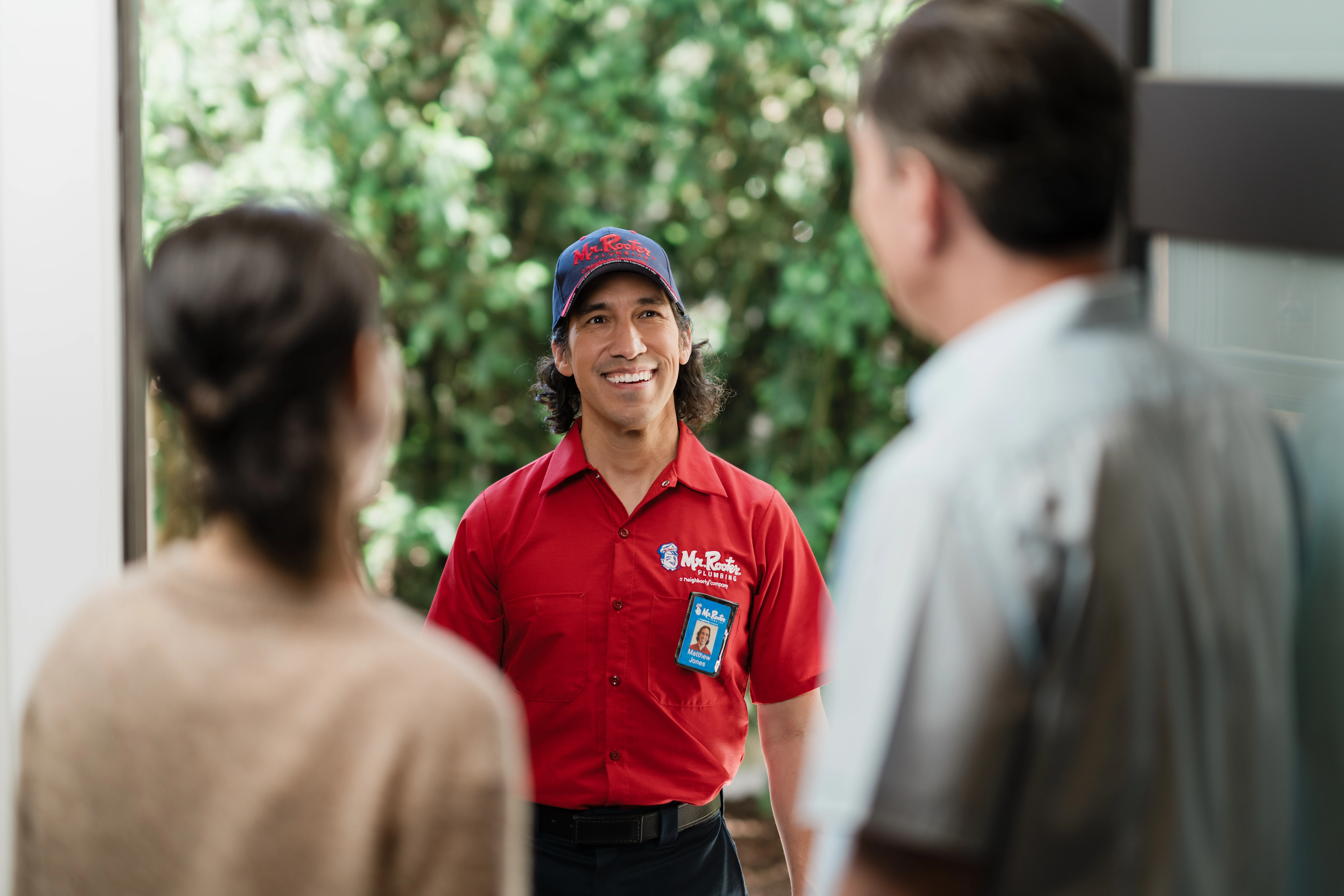 A Mr. Rooter Plumbing service professional greeting homeowners when arriving for professional sewer line repair.